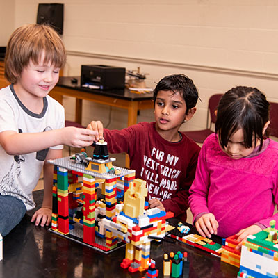 three children building a LEGO structure together