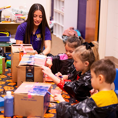 a college student doing some craft work with a few young children