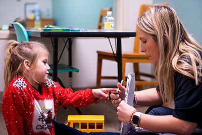 a student working with a young child, who is pointing out items on a piece of paper