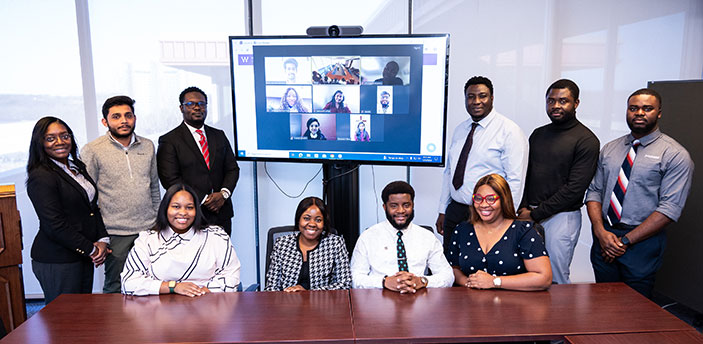 photo with 9 students in the internship program along with a Zoom meeting in the background of other interns