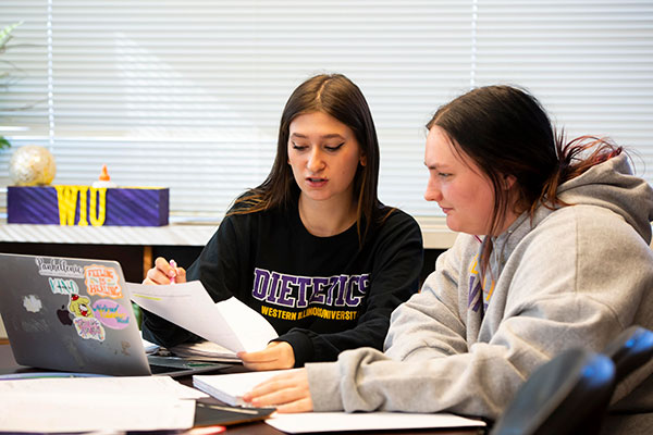 two students discussing a paper