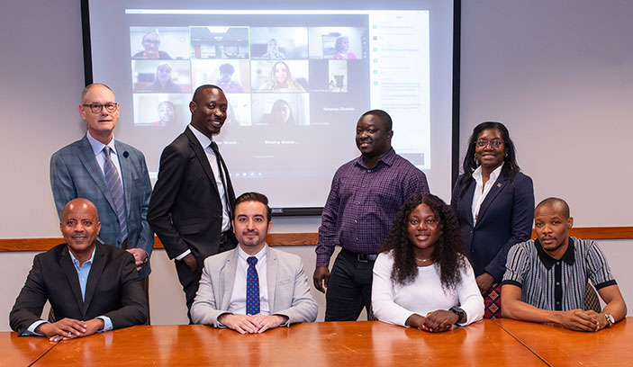 photo with 8 students in the internship program along with a zoom meeting in the background of other interns