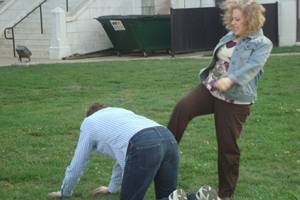 A woman pretends to kick a man on the ground.