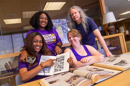 From left to right: Kessiena Erebi, Ifunanya Osondu, Abby Troxell-Skaggs and library specialist William Cook. Erebi is pointing at her mother's yearbook photo from her time at WIU. 